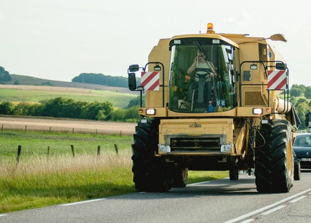 large yellow farm equpiment driving on road