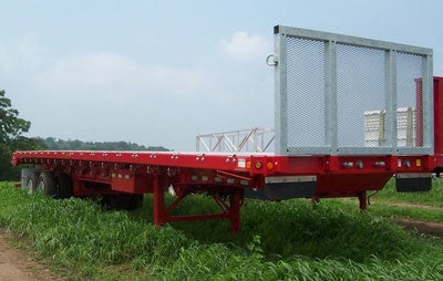 red flatbed trailer parked in grass field