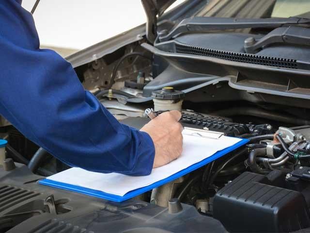 person filling out checklist on open engine vehicle