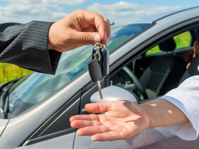 handing over new car keys to man sitting in vehicle